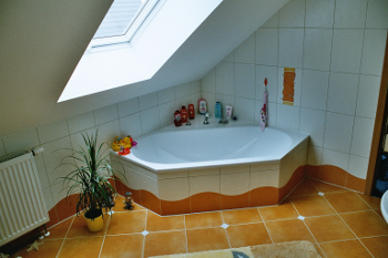 Abbildung eines Badezimmers mit rotgefliester Badewanne und Dachfenster.